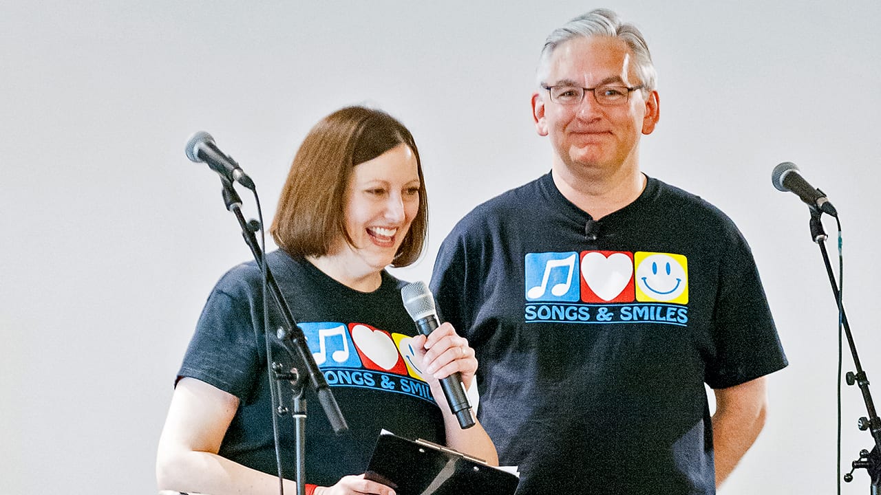 Sheryl speaking to audience and Eric listening